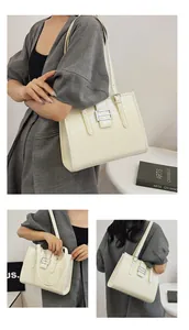 Macro shot of cream white tote bag featuring crocodile embossed texture and metal buckle detail