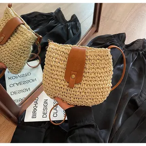 Détail du sac bandoulière en paille tressée avec rabat en similicuir brun et bouton pression