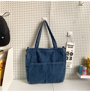 Dettaglio della borsa tote in denim blu scuro con doppie tasche frontali e cuciture