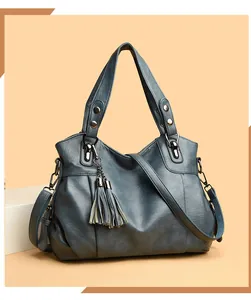 Detail of blue-grey leather tote bag showing soft texture, rivets and tassel charm