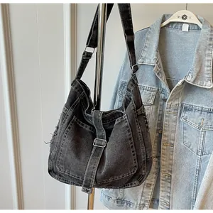 Detail of grey washed denim tote bag showing multi-pocket design and raw edges