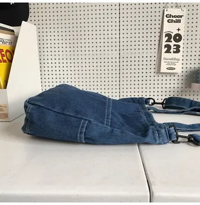 Dettaglio della borsa tote in denim blu con cuciture a contrasto e fibbie in metallo nero