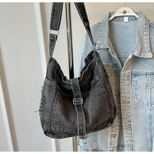 Detail of distressed black denim hobo bag featuring frayed edges and silver metal buckle
