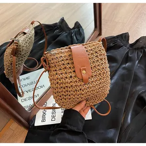 Détail du sac à bandoulière en paille tressée avec rabat en cuir marron et bouton