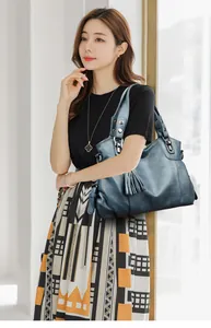Detail view of large navy blue tote bag with decorative tassels and leather texture