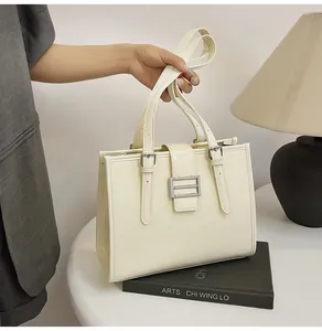 Close-up of the textured faux crocodile leather and silver buckle on a cream tote bag