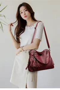 Detailed view of dark red leather tote featuring fringe charm and rivet accents