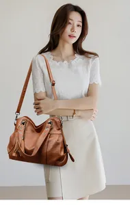 Detail of dark brown tote bag with leather texture, fringe tassel and silver metal hardware