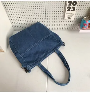 Dettaglio borsa tote in denim blu scuro con cuciture a contrasto e gancio in metallo