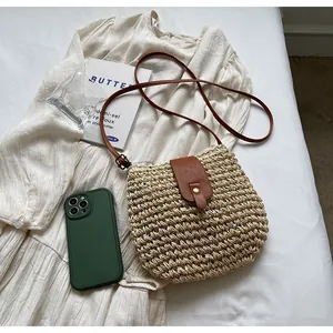Détail du sac bandoulière en paille avec rabat en cuir marron et boucle en métal