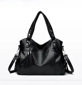 Front view of black vintage leather tote bag featuring long tassels and silver hardware
