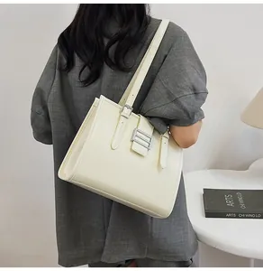 Detail of off-white crocodile embossed tote bag with silver buckle and shoulder straps