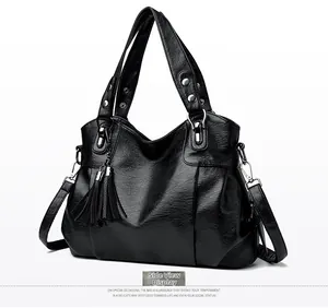 Detailed side view of black leather tote bag with silver hardware and tassel charm