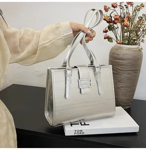 Detail shot of silver faux crocodile texture tote bag with metallic buckle and leather straps