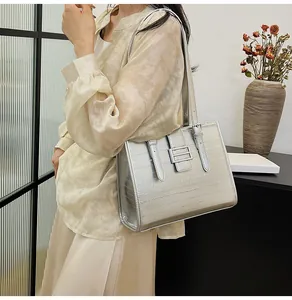 Detail view of silver tote bag with textured letter embossing and buckle straps