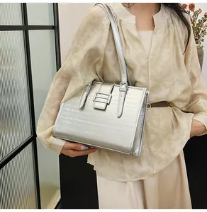 Detailed view of silver tote bag featuring horizontal embossed texture and metal buckle