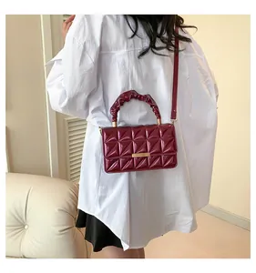 Détail du sac à main en cuir verni bordeaux avec matelassage et poignée froissée