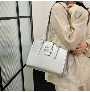 Detail of silver textured tote bag featuring horizontal stripes and metal buckle on shoulder