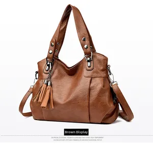 Side view of large brown leather tote bag featuring stylish long tassels and silver hardware