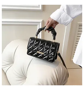 Vue détaillée du sac en cuir verni matelassé noir avec ferrures dorées et anse plissée
