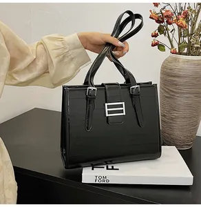 Detail of glossy black textured leather tote bag with silver metallic hardware buckle