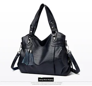 Detail view of deep blue tote bag with PU leather texture, tassels, and silver hardware