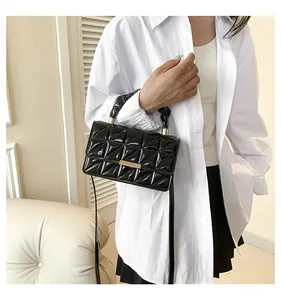 Sac à bandoulière noir verni matelassé avec boucle dorée porté par un mannequin