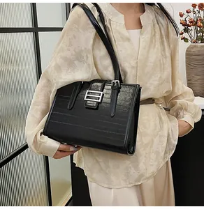 Detailed close-up of a black textured baguette bag with a silver square buckle on a model