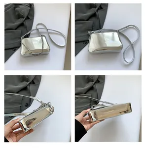 Detail of silver mirror crossbody bag showing metallic finish, logo, and chain strap