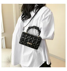 Détail du sac en cuir verni matelassé noir avec poignée froncée et garniture dorée
