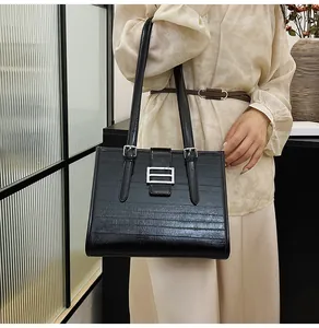 Detail of black faux crocodile leather tote bag featuring silver buckle and slim straps