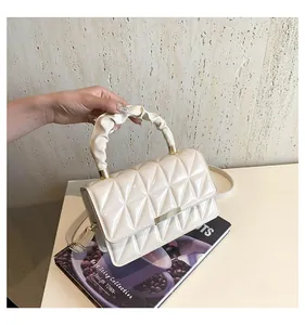 Détail d'un sac à main matelassé beige avec poignée plissée posé sur un magazine chic