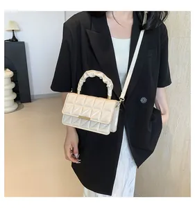Sac à main chic en cuir verni matelassé crème présenté sur un mannequin de mode