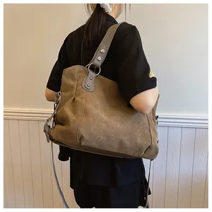 Détail d'un grand sac fourre-tout en toile kaki vintage avec anses en cuir gris et boucle