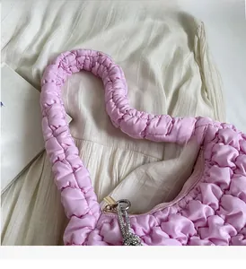 Detail of pink quilted cloud bag featuring comfortable handle and soft pleated texture