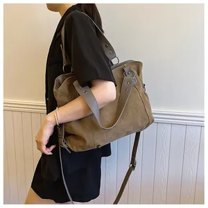 Vue latérale d'un grand sac cabas en toile marron avec bandoulière réglable sur modèle