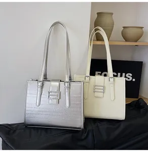 Detail view of large French tote bags in silver and off-white with sleek metal buckles