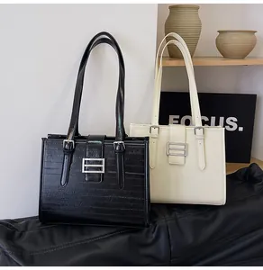 Macro detail of high-shine leather texture and silver rectangular buckle on tote bags