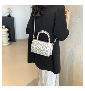 Sac bandoulière argenté matelassé avec poignée froncée porté à l'épaule en intérieur