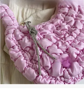Detailed shot of the light purple pleated cloud bag featuring a sparkly rhinestone bow charm