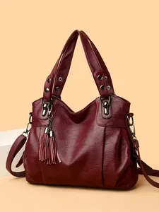 Large burgundy tote bag with leather tassels and silver hardware on a minimalist background