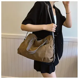 Détail du grand sac cabas kaki foncé avec des lanières en cuir gris et des ferrures métalliques