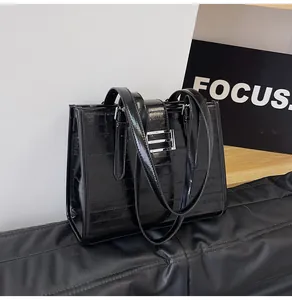 Detail of glossy black faux crocodile skin tote bag with silver metallic bar buckle
