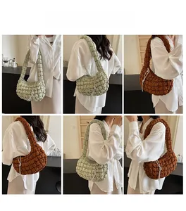 Detail of quilted cloud-style puffer bag showing pink plaid texture and soft shoulder strap