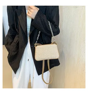 Detail of woven straw shoulder bag featuring silver chain strap and leather trim accents