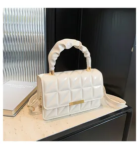 Détail du sac en cuir verni crème avec matelassage en losanges et poignée chouchou