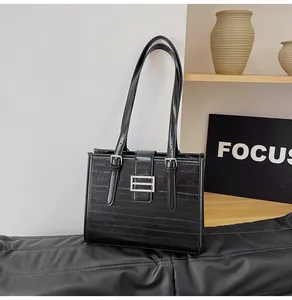 Detail of black textured tote bag with silver square buckle and double shoulder straps