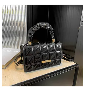 Détail du sac matelassé en cuir verni noir avec poignée froncée et accents dorés