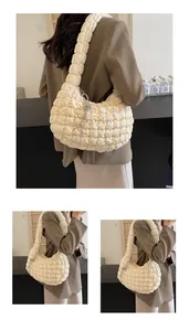 Detail of a beige quilted bubble cloud bag with silver rhinestone knot decoration