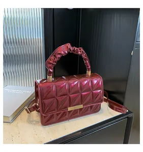 Détail du sac en cuir verni bordeaux avec motif matelassé et poignée froncée